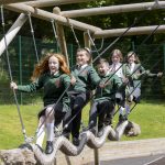 three school girls and two school boys play on new play park equipment