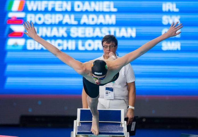 Male swimmer jumping off diving board