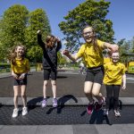 four school girls play on new play park equipment