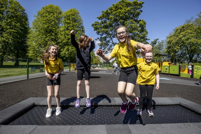four school girls play on new play park equipment