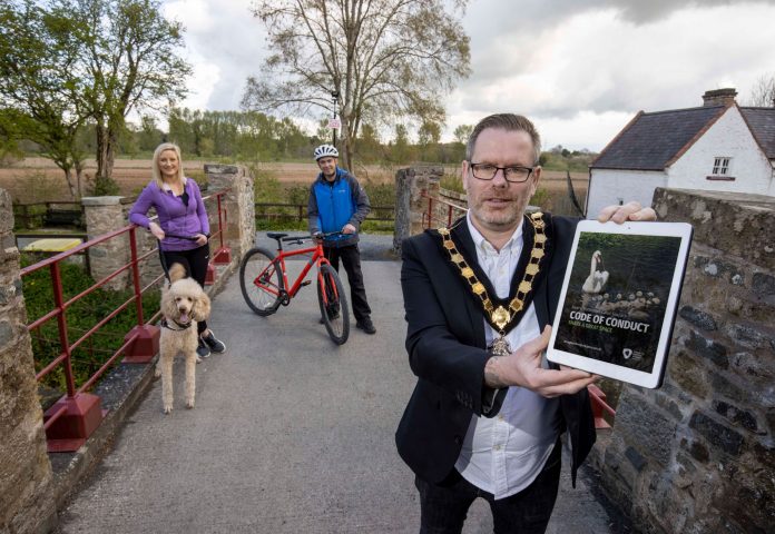 Male Lord Mayor pictured with a female dog walker and male cyclist outside on a path