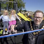 Male Lord Mayor cuts ribbon to new play park with two young girls in background