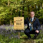The Lord Mayor holding a 'Nature at its best' poster surrounded by bluebells