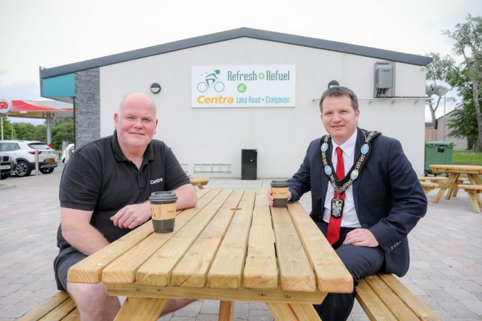 Two men sitting on picnic bench outside