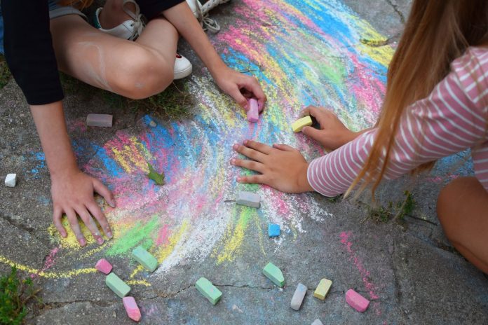 two teens using chalk on pavement