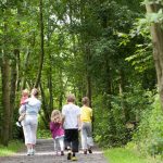 Female and 4 young children walking in the forest.