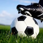 Photo shows a football with a boot resting on top of it