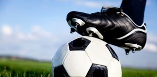 Photo shows a football with a boot resting on top of it