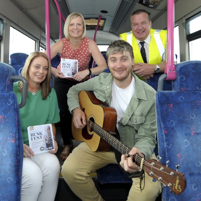 A guitarist with three people on a bus.