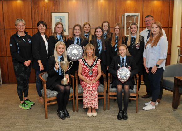 Large group of people sitting and standing with trophies.