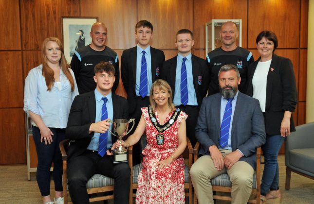 Small group of people sitting and standing with a trophy.