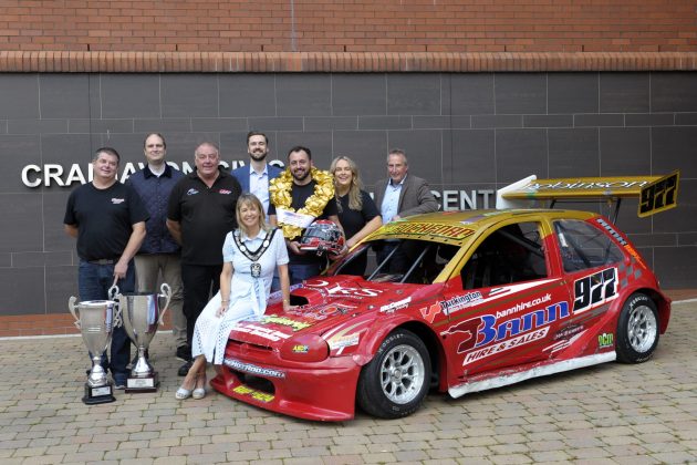 Small group of people pictured beside a racing car.
