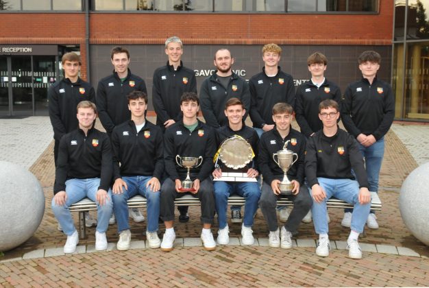 Male hockey team with three trophys.