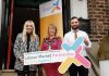 Three people standing holding a sign for Labour Market Partnerships
