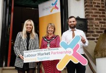 Three people standing holding a sign for Labour Market Partnerships