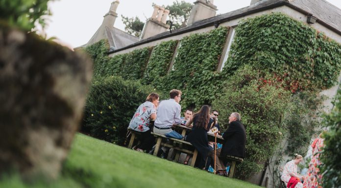 Picture of outside of an old house with people sitting at a table