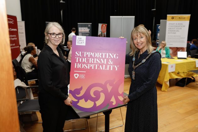 Two women holding a sign for Tourism and Hospitality