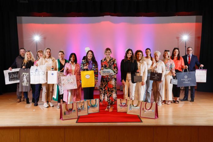 Local business owners in a fashion show holding shopping bags