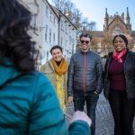 3 people listening to a tour guide.