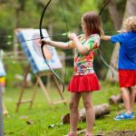 A young girl and boy doing archery.