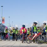 A large group of young cyclists wearing high-vis vests.