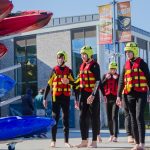 Four young people wearing wetsuits and ready to go canoeing.