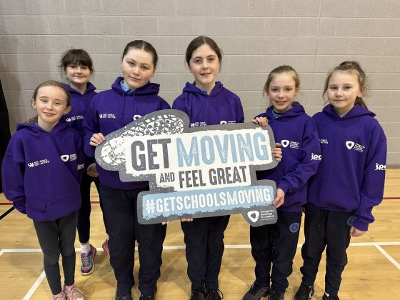 A group of school girls holding a "get moving" sign.