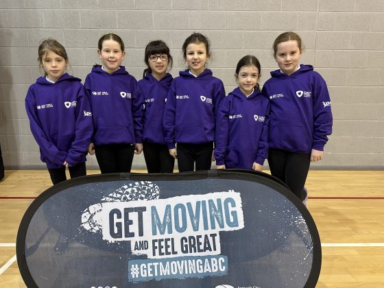 A group of school girls standing in front of a "get moving" sign.