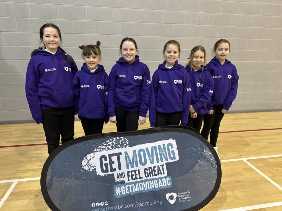 A group of school girls standing in front of a "get moving" sign.