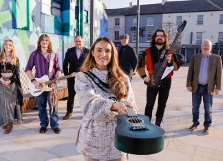 Group of males and females standing outside holding musical instruments