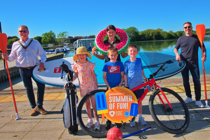 Teddy Tails Group or people smiling in the sunshine with a range of watersports equipment and sports equipment.
