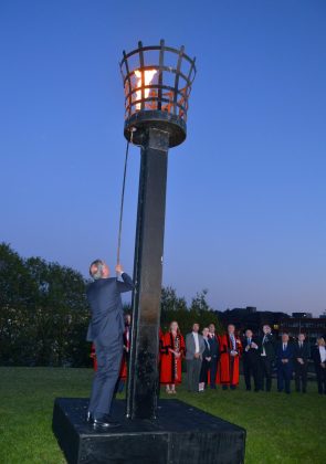 Man lighting a beacon outside.