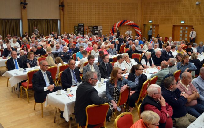 Large group of people seated inside.