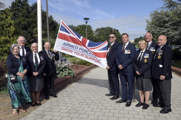 Small group of people standing beside flag