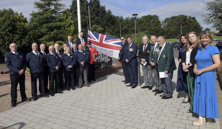 Large group of people standing beside a flag