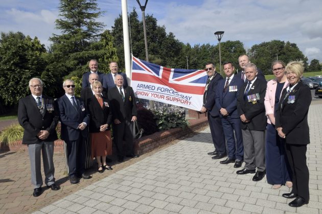 Group of people standing beside a flag.