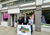 Three people standing outside Gasp Boutique clothes shop with a sign saying Shop ABC Gift Card