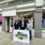 Three people standing outside Gasp Boutique clothes shop with a sign saying Shop ABC Gift Card