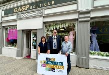 Three people standing outside Gasp Boutique clothes shop with a sign saying Shop ABC Gift Card