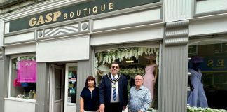 Three people standing outside Gasp Boutique clothes shop with a sign saying Shop ABC Gift Card