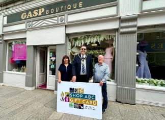 Three people standing outside Gasp Boutique clothes shop with a sign saying Shop ABC Gift Card