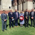 Five males and one female standing outside with a wreath
