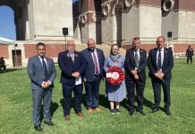 Five males and one female standing outside with a wreath