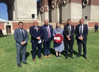 Five males and one female standing outside with a wreath