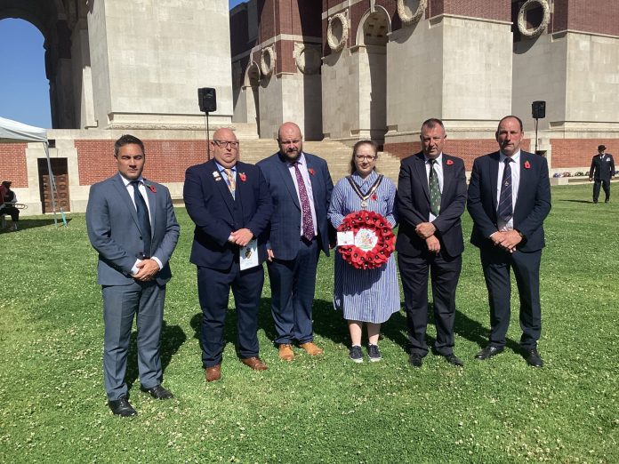 Five males and one female standing outside with a wreath