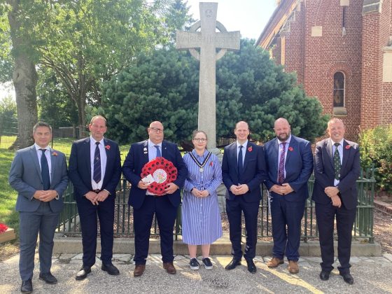 Six males and one female outside with a wreath.
