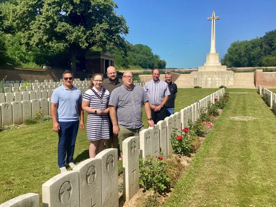 Five males and one female outside in a cemetery.