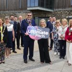 12 people standing with 2 people holding a board saying Ultimate Pitch.