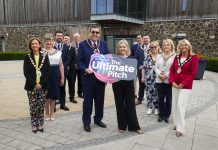 12 people standing with 2 people holding a board saying Ultimate Pitch.