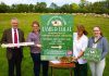 Four people standing in a field with food and a sign saying Lamb and Local.
